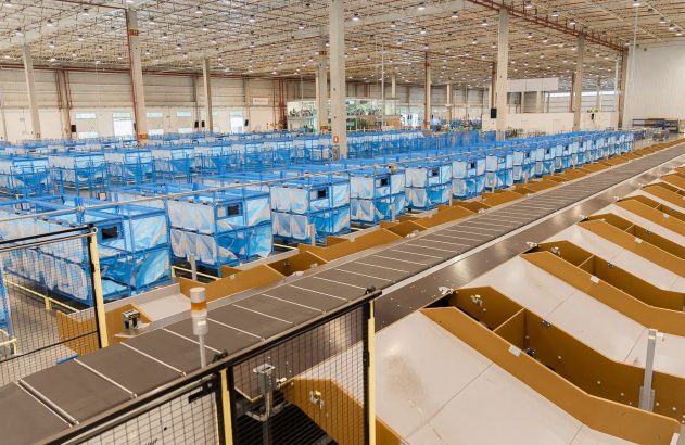 Armazém de logística com longas esteiras transportadoras e filas de caixas de triagem azuis em um sistema automatizado.