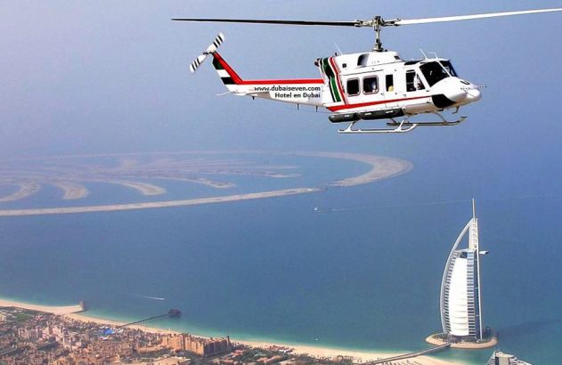 Helicóptero voando sobre Dubai, mostrando o Burj Al Arab e as ilhas Palm ao fundo.