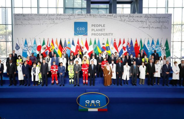 Foto de grupo de líderes mundiais e autoridades em cúpula do G20, com bandeiras e logo G20 ao fundo.