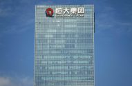Prédio de vidro da Evergrande Group com o logo no topo sob céu azul.