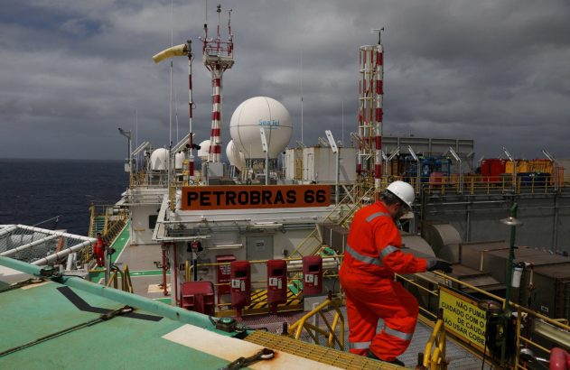 Trabalhador de laranja em plataforma Petrobras 66 no mar, com domos Sea Tel e antenas.