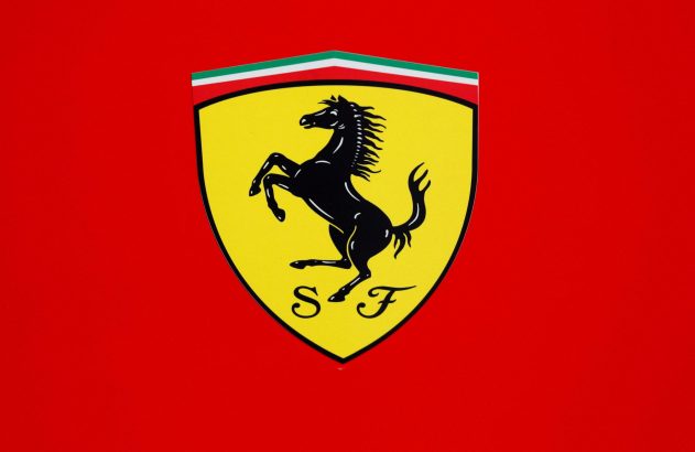 Logotipo da Ferrari: cavalo preto empinado em escudo amarelo, com faixas verde, branco e vermelho. Fundo vermelho.