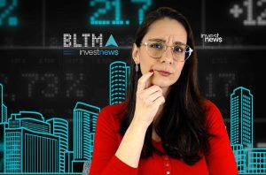 Mulher de óculos e camisa vermelha, pensativa, diante de painel digital financeiro com números e contornos de edifícios.