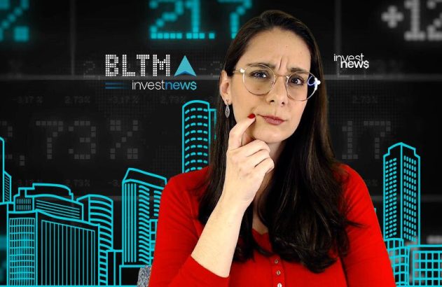 Mulher de óculos e camisa vermelha, pensativa, diante de painel digital financeiro com números e contornos de edifícios.