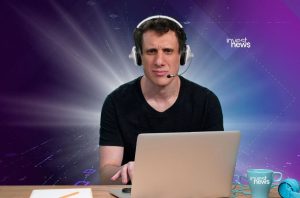 Homem de headset, expressão séria, usa notebook em fundo digital roxo. Logo 'invest news'.