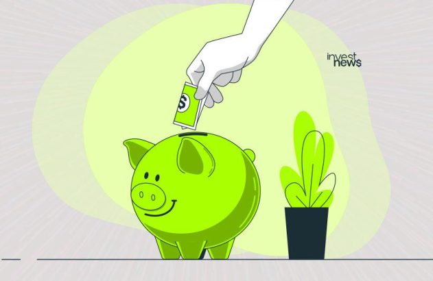 Mão inserindo dinheiro em cofrinho verde.