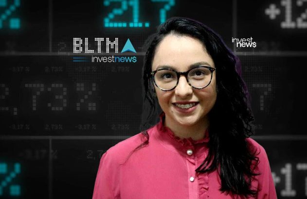 Apresentadora sorridente de óculos em estúdio com tela digital de dados financeiros e logo Investnews ao fundo.