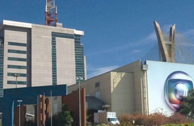 Vista externa do complexo de estúdios da TV Globo em São Paulo, com seu logo e a Ponte Estaiada ao fundo.