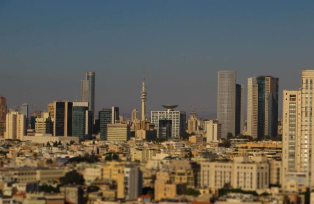 Skyline de uma cidade com arranha-céus e edifícios variados, utilizando efeito tilt-shift, que dá aspecto de miniatura.
