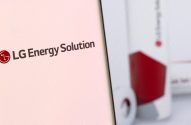 Logo LG Energy Solution em tela e baterias cilíndricas vermelhas desfocadas.