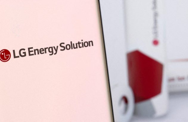 Logo LG Energy Solution em tela e baterias cilíndricas vermelhas desfocadas.