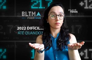 Mulher com expressão de dúvida e mãos abertas, em frente a painel digital com números e texto "2022 difícil... até quando?".