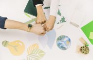 Três punhos juntos em uma mesa branca com recortes ecológicos.