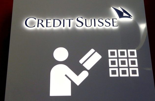 Sinal da Credit Suisse. Pessoa inserindo cartão em caixa eletrônico com teclado na imagem.
