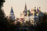 Izmailovsky Kremlin: complexo estilo castelo, torres e telhados coloridos. Pessoa em ponte entre árvores.