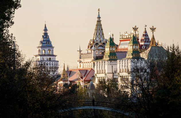 Izmailovsky Kremlin: complexo estilo castelo, torres e telhados coloridos. Pessoa em ponte entre árvores.