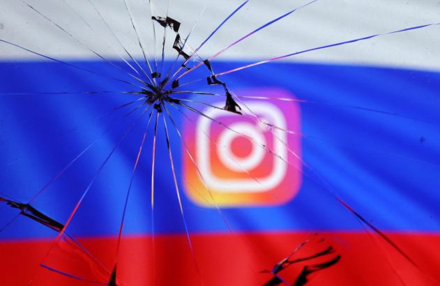 Vidro estilhaçado com impacto central, sobre o logo do Instagram e a bandeira russa ao fundo.