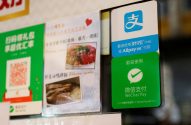 Placas em loja exibindo métodos de pagamento digital (Alipay, WeChat Pay), QR code para promoções e parte de um cardápio.