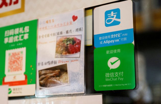 Placas em loja exibindo métodos de pagamento digital (Alipay, WeChat Pay), QR code para promoções e parte de um cardápio.
