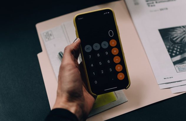 Uma mão segurando um celular aberto na tela da calculadora