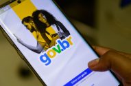 Smartphone com app gov.br aberto. Mão posiciona dedo para tocar botão "Entrar com gov.br". imposto de renda