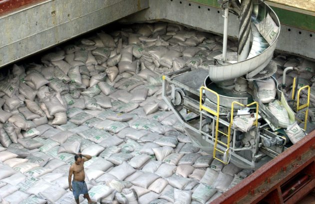 Porão de navio: sacos de açúcar movimentados por espiral e esteiras. Homem entre a carga.
