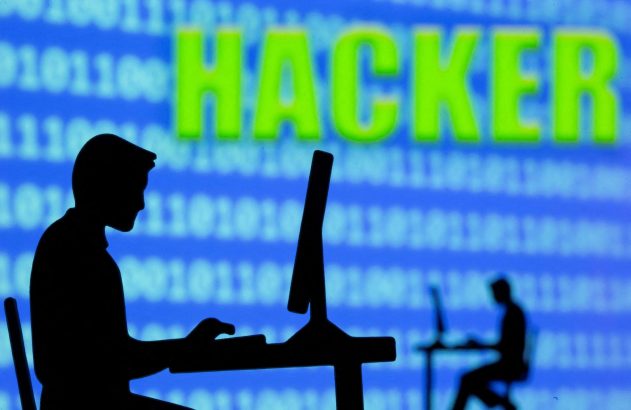 Silhuetas de pessoas em computadores; fundo azul com código binário e palavra HACKER em verde.
