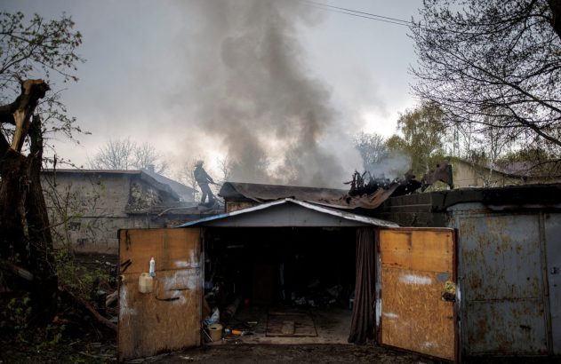 Bombeiro combate fogo e fumaça em telhado de garagem.