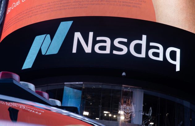 Logotipo da Nasdaq em tela digital iluminada em ambiente noturno. Acima, texto oficial em vermelho.