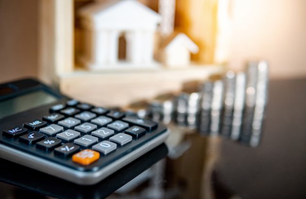 Calculadora em cima da mesa com moedas ao redor