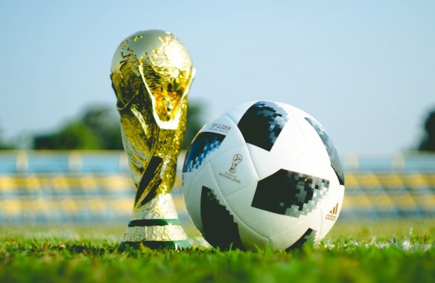 Taça da copa do mundo ao lado de uma bola de futebol