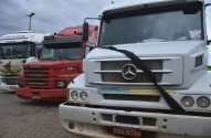 Caminhões estacionados. O branco Mercedes-Benz em primeiro plano exibe uma faixa preta na grade frontal.