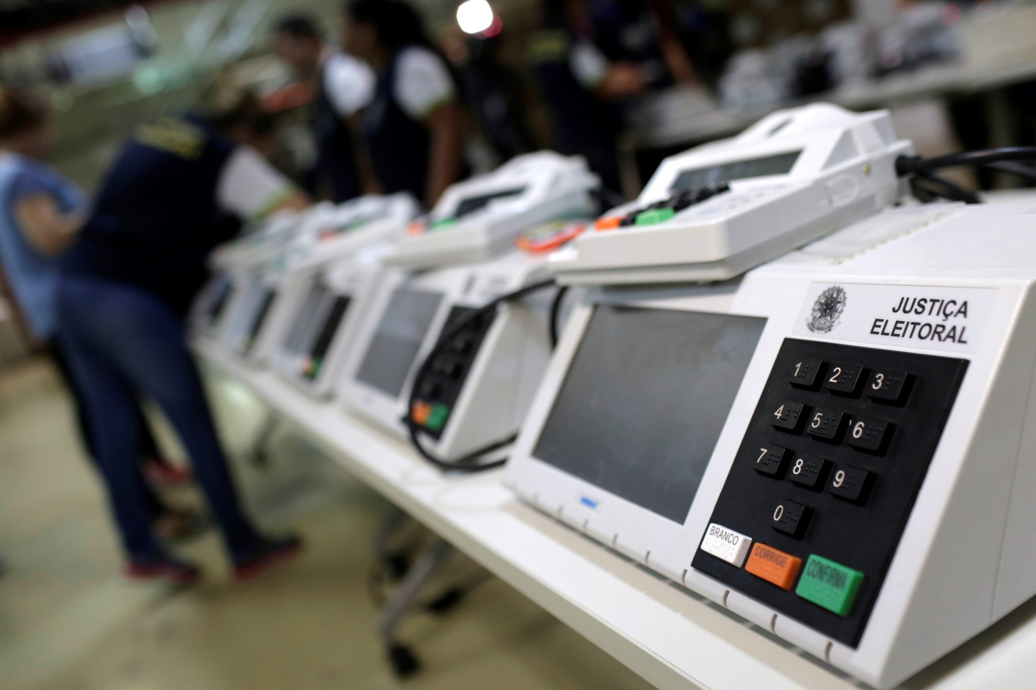 urna eletronica com fiscal ao fundo