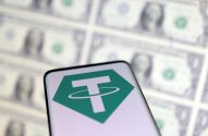 Smartphone exibe o logo do Tether (USDT) com notas de dólar dos EUA borradas ao fundo.