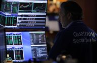 Homem observa múltiplos monitores com dados financeiros. Na camisa: "QuattroM Securities Inc".