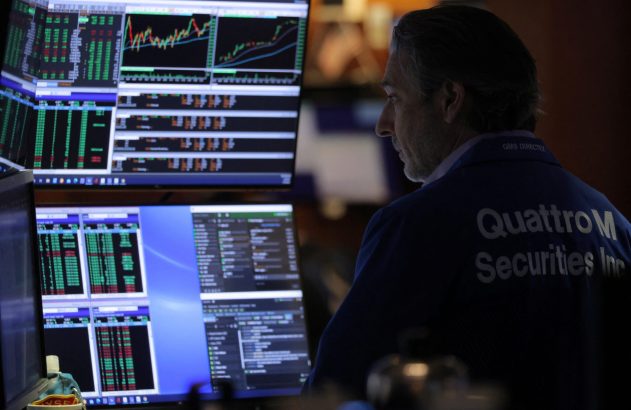 Homem observa múltiplos monitores com dados financeiros. Na camisa: "QuattroM Securities Inc".
