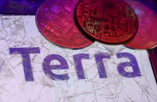 Tela de dispositivo rachada com moedas de cripto vermelhas e a palavra 'Terra' em roxo.