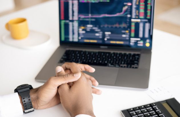 Homem com mãos em cima do notebook acompanhando operação da bolsa de valores