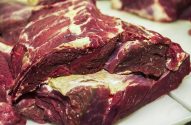 Vários grandes cortes de carne vermelha crua em uma superfície branca.