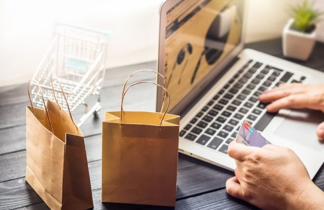 Pessoa faz compra online segurando cartão de crédito