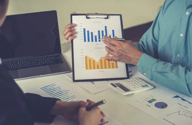 Duas pessoas em uma reunião, uma mostrando gráfico para outra