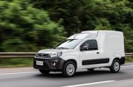 Furgão comercial branco Partner Rapid em movimento na estrada, com fundo de árvores borrado.