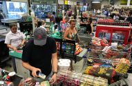 Supermercado: clientes pagando compras em múltiplos caixas com carrinhos cheios.