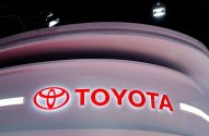 Logotipo vermelho e branco da TOYOTA em um estande curvo iluminado.