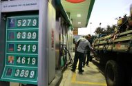 Frentista abastece caminhão em posto; painel com preços de gasolina, diesel e etanol.