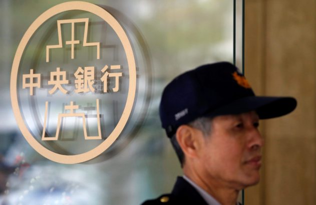 Homem de boné em frente ao logo em caracteres chineses do Banco Central, em porta de vidro.
