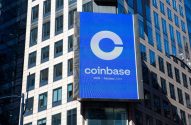 Um letreiro digital grande da Coinbase com seu logo 'C' e nome, junto a 'COIN Nasdaq Listed', em um edifício urbano.