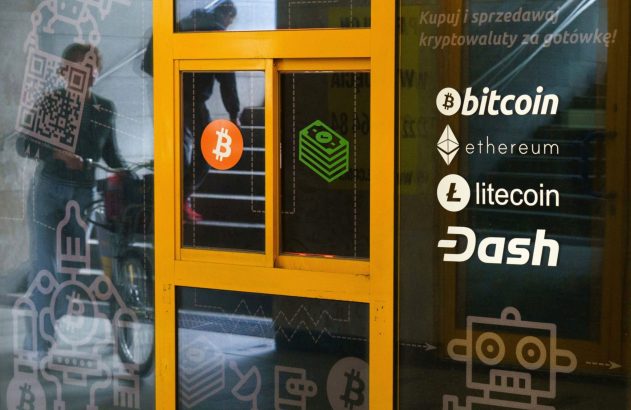Vitrine anuncia compra/venda de criptomoedas (Bitcoin, Ethereum, Litecoin, Dash) e reflete pessoa com bicicleta.