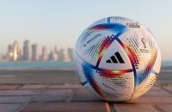 Bola de futebol Al Rihla da Copa do Mundo 2022 no chão, com a cidade de Doha e o mar ao fundo.