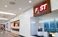 Fachada da loja FAST SHOP em um corredor de shopping, com letreiro proeminente e vitrine com produtos.